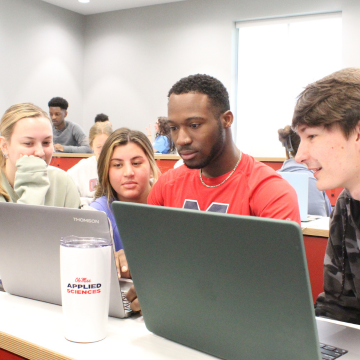 Four diverse social work students sitting around laptop discussing school work