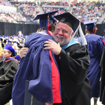 Professor hugging student at graduation