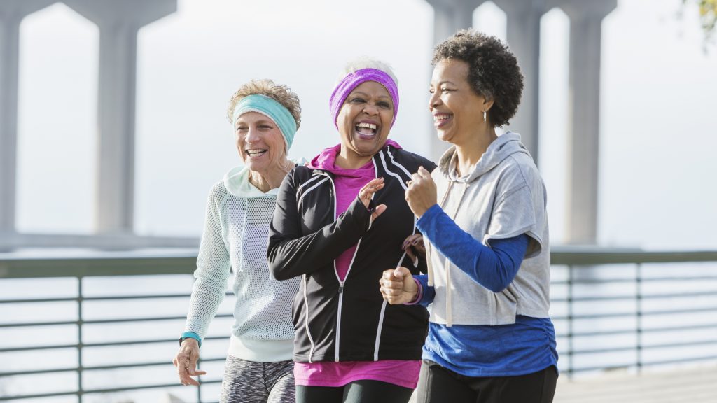 Three mature women power walking together on waterfront
